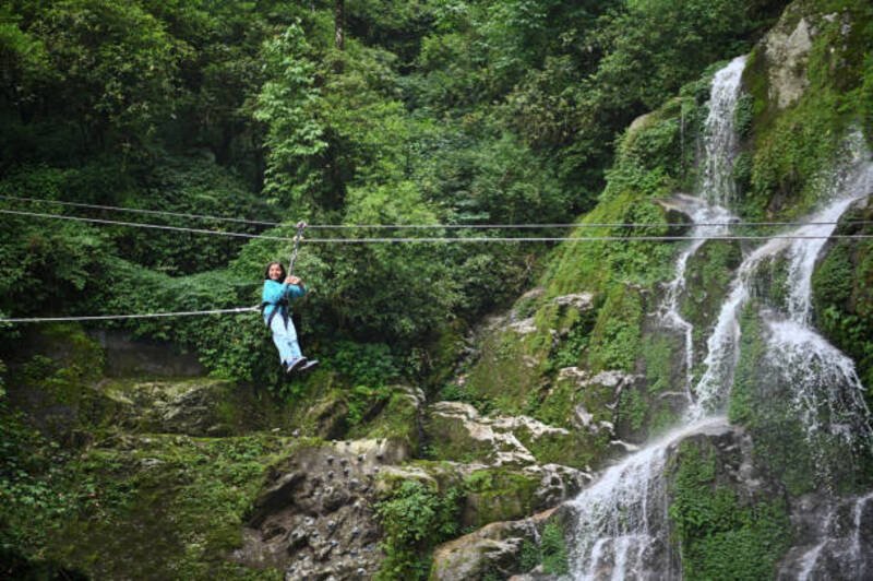 A girl zip-lining near a waterfall in Gangtok, Sikkim