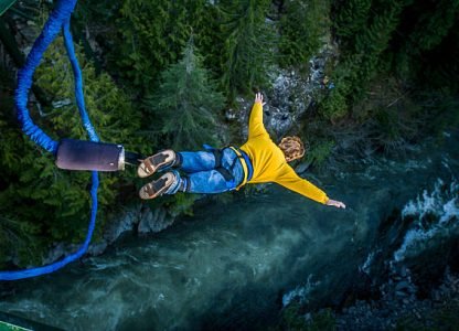 Young man bungee jumping over river.